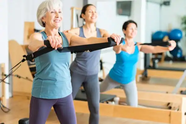 Toning Arms After 60: Empowering Womens Fitness Through Effective Weight Training 2 older woman doing weight training Surrey and resistance in the gym to tone upper arms